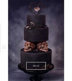 a three tiered cake with skulls on it's sides and hearts above the top