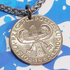 a silver coin is on a chain with blue and white flowers in the back ground