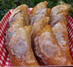 several pastries sitting in a basket on top of a red and white checkered table cloth