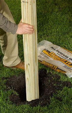 a man is digging in the ground with a shovel and wooden post on top of it