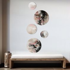 three circular mirrors hanging on the wall above a bench in front of a white wall