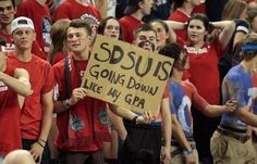 a group of young people holding signs in front of a crowd at a sporting event