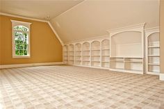 an empty room with built - in bookcases and carpeted flooring is shown