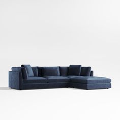 a blue sectional sofa with pillows on the top and bottom, in front of a white wall