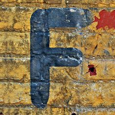 a brick wall with a painted letter f on it