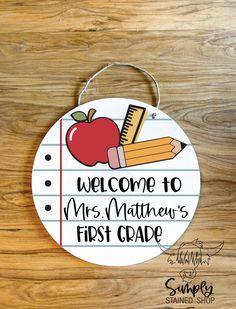 a wooden sign that says welcome to mrs mathew's first grade with an apple and pencil