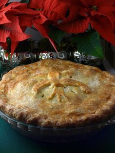 a pie sitting on top of a table next to poinsettis