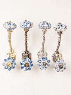 four antique blue and white knobs are lined up against a white background with gold accents