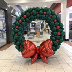 a large balloon wreath in the middle of a shopping mall with red and green balloons