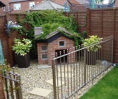 a dog house in the middle of a yard with a fence and green grass around it