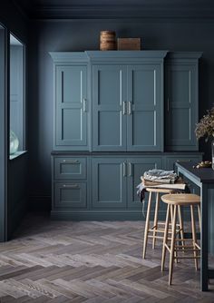 a kitchen with blue cabinets and stools in the center, wood flooring on the other side