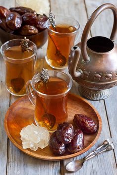 tea and fruit on a wooden plate next to a silver tea pot with spoons