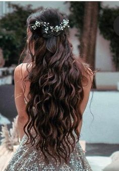 the back of a woman's head with long hair and flowers in her hair