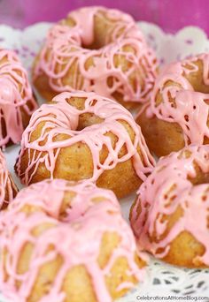 there are many donuts with pink icing on the top one is glazed and drizzled