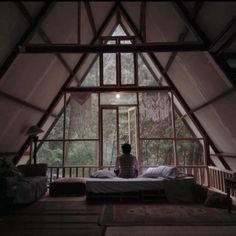 a person sitting on top of a bed in a room filled with lots of windows