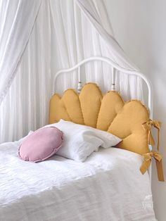 a white bed topped with pillows and a pink pillow on top of it's headboard