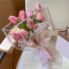 a bouquet of pink tulips sitting on top of a white chair next to a box