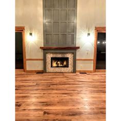 an empty room with wood floors and a fireplace