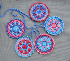 four crocheted doily hanging on a gray cloth with blue and red trim