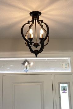 a chandelier hanging from the ceiling in front of a door with three lights on it