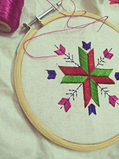 a cross stitched on to a piece of fabric next to a spool of thread