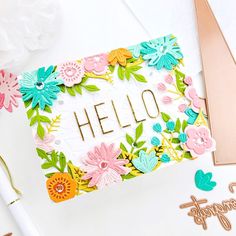 a card with the word hello written on it next to some paper flowers and scissors