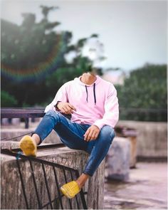 a man sitting on top of a wooden fence next to a park bench wearing yellow shoes