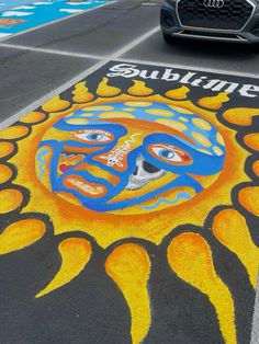 a car driving down a street next to a chalk drawing on the ground with an image of a sun