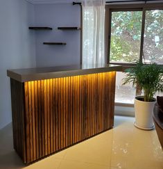 a wooden cabinet with lights on it in front of a window and potted plant