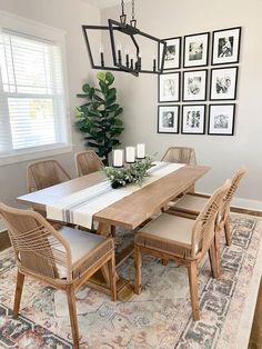 a dining room table with chairs and pictures on the wall behind it, along with a rug