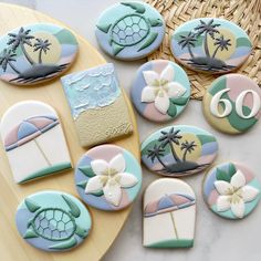 decorated cookies with palm trees and beach scenes are on a tray next to a wicker basket