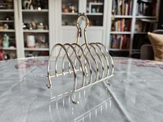 a metal rack sitting on top of a table in front of a book shelf filled with books