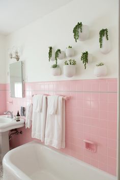 a bathroom with pink tiles and white towels hanging on the wall next to a bathtub