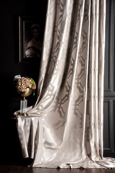 a vase with flowers sitting on top of a table next to a curtain