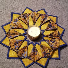 a candle sitting on top of a yellow and blue quilt