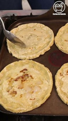 four flat breads are being prepared in a pan with a spatula on top