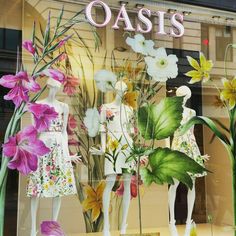 a window display with flowers and mannequins in it