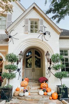 pumpkins and spider decorations on the front steps of a house