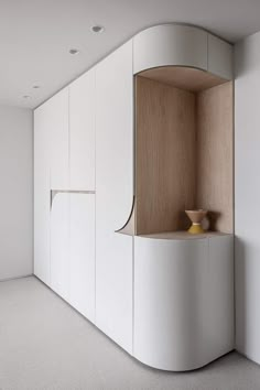 an empty room with white cupboards and a yellow vase on the counter in front of it