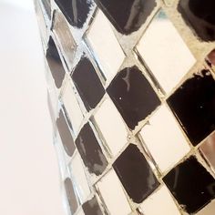 the reflection of a person's hand in a mirror with black and white tiles