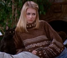 a woman sitting on top of a couch next to a black cat