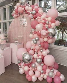 a pink and silver balloon arch in the shape of a tree