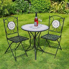 a table and chairs in the grass with a bottle of wine