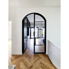 an arched glass door leading to a bedroom with hardwood floors and white walls, along with wooden parquet flooring