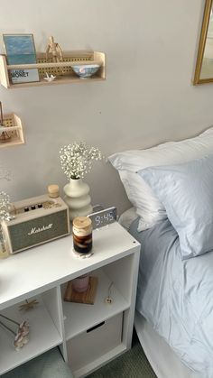 a bed with white sheets and pillows next to a night stand on a nightstand in a bedroom