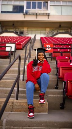 a woman sitting on the steps in front of red stadium seats with her legs crossed