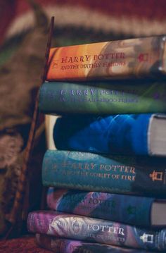 a stack of harry potter books sitting on top of each other in front of a bed