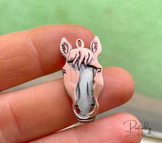 a person is holding a small animal shaped charm in their hand, with the image of a zebra on it's face