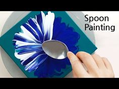 someone is using spoons to paint a flower on a paper box with blue and white flowers