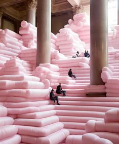 people sitting on giant pink mattresses in a building